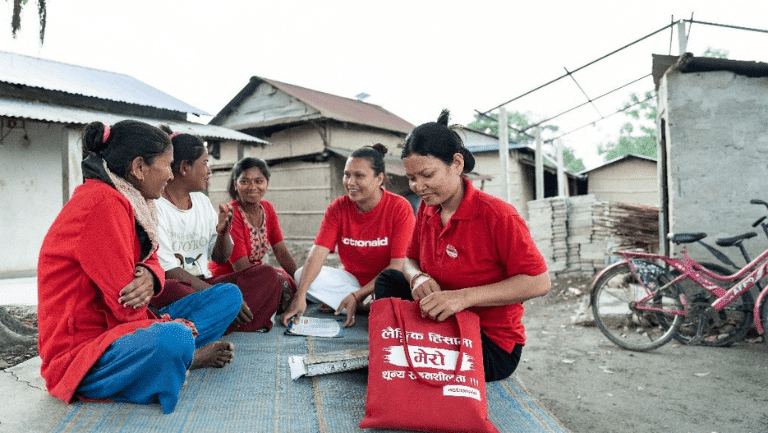 Women sitting in a circle outdoors, who are part of an ActionAid Safe Space group in Chitwan, Nepal.