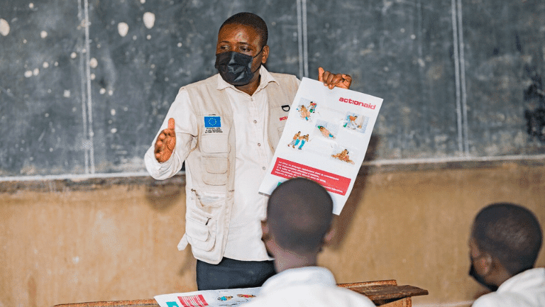 Teacher using an educational booklet to teach students about Ebola prevention.